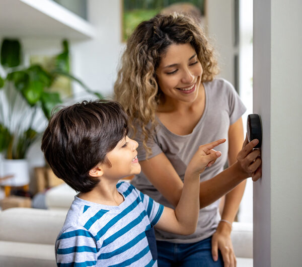 Happy mother and son at home using a smart thermostat